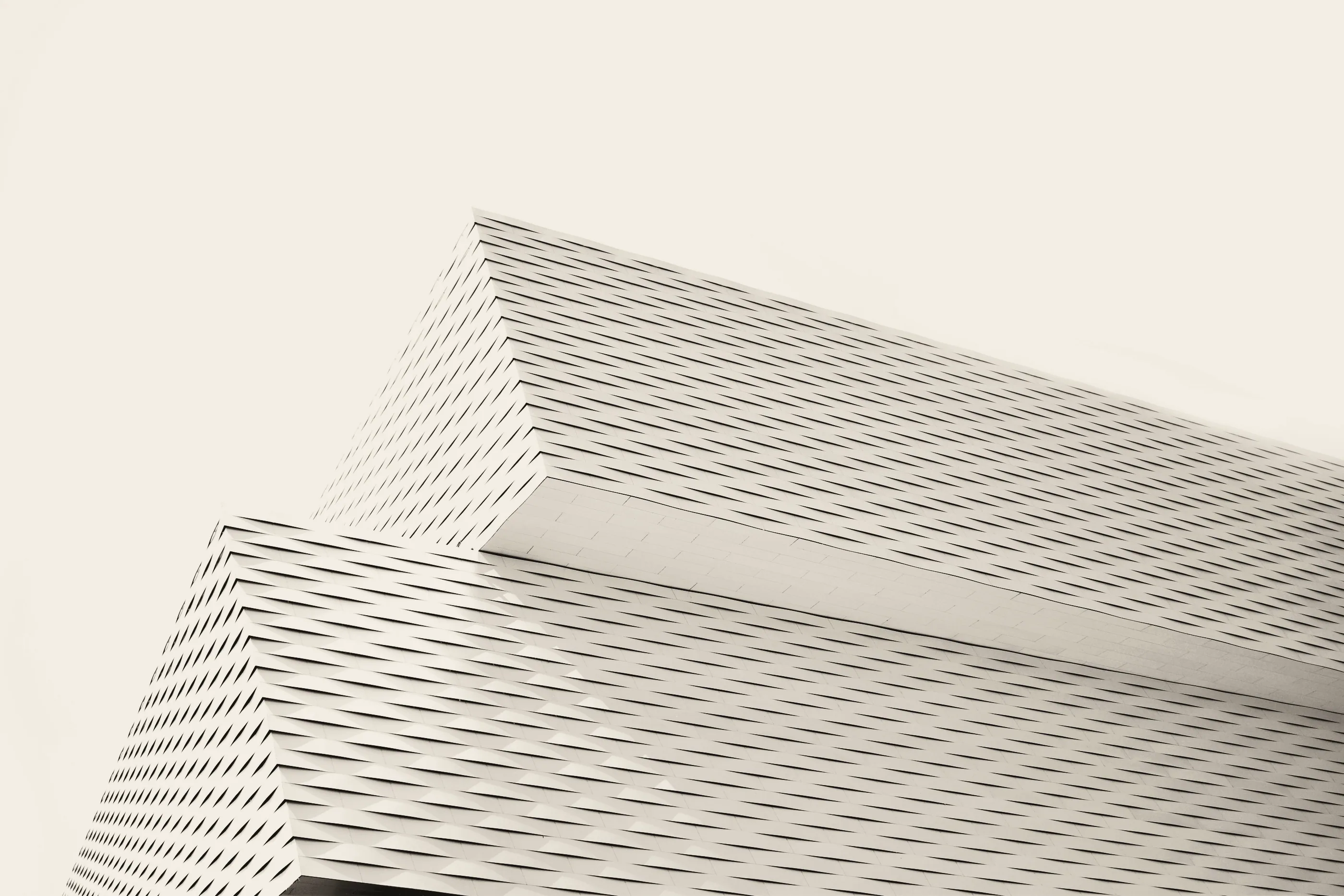 Faceted white building facade against pale sky